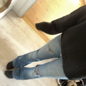 Replay bootcut jeans med slitningar - Säljer ett par ljusblå bootcut jeans från Replay med snygga slitningar på knäna och snygga detaljer på bakfickorna. Jeansen har låg midja och klassisk femficksdesign. I strl 27/30. Har en pytteliten reva som inte syns och är lagad, kontakta för bild på de