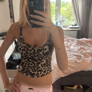 Leopardmönstrad linne-topp - Säljer en snygg leopardmönstrad linne-topp med smala axelband och figurnära passform. Toppen har beige och bruna toner med svarta detaljer i mönstret. Har aldrig använt denna bara testad🥰