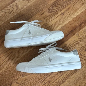 Vita Polo Ralph Lauren skor - Vita silver glittriga Polo Ralph Lauren skor. Använda 1 gång men har inga tecken på slitage! Förutom undertill där det är lite smutsigt men inte alls mycket. Väldigt stilrena skor som passar till det mesta!! Köpta för 1015 kr