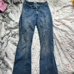 Blå bootcut jeans från weekday X cherrie - Säljer ett par klassiska blå jeans med bootcut-silhuett och snygga söm-detaljer längs benen. Jeansen har normal midja till lägre midja, bälteshällor och dragkedja framtill. Passar långa. Jag är 172 cm lång. 