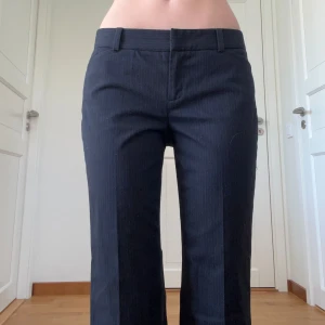 Lågmidjade kostymbyxor  - Snygga svarta kostymbyxor med diskret randigt mönster. Klassisk look med pressveck och två fickor bak. Perfekta för en clean och stilren outfit.