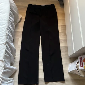 Svarta kostymbyxor från Madlady - Säljer ett par svarta kostymbyxor från Madlady i storlek 36. Byxorna har raka ben, pressveck och klassisk stängning med hake och dragkedja. Perfekta för en clean och stilren look. Lite knottriga inne vid låren. 