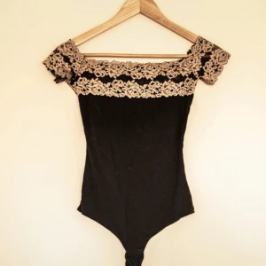 Svart body med spets från Intimissimi - Supersnygg svart body från Intimissimi med offshoulder och breda spetsdetaljer i beige över axlarna. Storlek S🌸