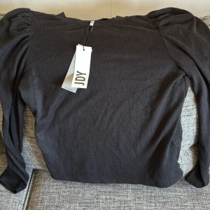 Svart långärmad topp med puffärm JDY - Svart långärmad topp från JDY med trendiga puffärmar som ger en snygg siluett. Enkel och stilren design, perfekt att matcha med jeans eller kjol. Mjukt material som känns skönt mot huden och passar året runt. Och jag råka beställa fel storlek så den är helt oanvänd. 