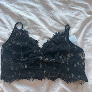 Svart spetsig korsettopp från Amisu - Supersnygg svart korsettopp från Amisu i spets med blommigt mönster och tunna axelband. Toppen har dragkedja bak och är fodrad med beige mesh på insidan. Perfekt för att lyfta vilken outfit som helst med sin coola spetskant och detaljer.