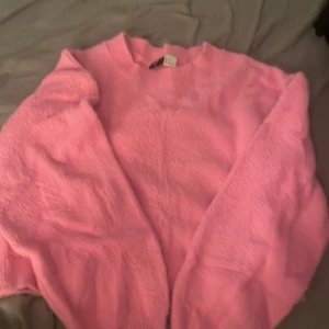 Rosa fluffig stickad tröja H&M Divided - Supermysig rosa stickad tröja från H&M Divided. Tröjan har lång ärm, rund halsringning och är gjord i ett fluffigt material som känns extra mjukt. Perfekt för dig som vill ha en färgklick i garderoben och gillar oversized vibes.