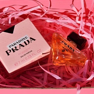 Prada Paradoxe Eau de Parfum 7ml - Prada Paradoxe Eau de Parfum i en snygg trekantig glasflaska med svart kork. Doften kommer i en ljusrosa kartong och flaskan rymmer 7 ml. Perfekt storlek för att ta med i väskan och en lyxig detalj på sminkbordet.