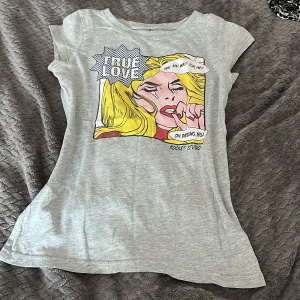 Vinted tröja - Grå t-shirt från Rocket Studio med färgglatt pop art-tryck framtill och texten 'TRUE LOVE'. T-shirten har rund halsringning och korta ärmar. Materialet känns mjukt och lätt, perfekt för en chill look. S men tight i bysten❤️