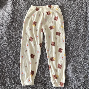 Söta mjukisbyxor med björnmönster - Supermysiga krämfärgade mjukisbyxor med gulligt björnmönster i brunt och gult. Byxorna har resår i midjan och vid bensluten för extra komfort. Tillverkade i mjuk bomullsblandning med lite stretch, perfekta för chill dagar hemma. Det står 5XL-6XL, men dom är mer L