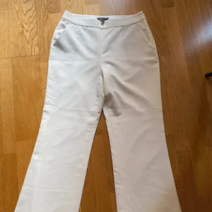 Vita kostymbyxor med bootcut - Snygga vita kostymbyxor från ESPRIT med bootcut-silhuett. Byxorna har hög midja, sidofickor och diskret dragkedja i sidan. Tillverkade i ett mjukt tyg som ger en clean och stilren look. Aldrig använda men prislapp saknas.