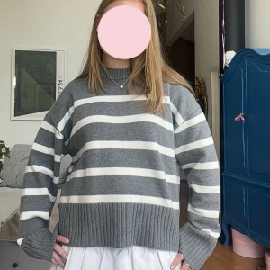 Gråvit randig stickad tröja H&M - Supermysig stickad tröja från H&M i grått och vitt med breda ränder. Perfekt att slänga på sig när det är kyligt ute. Passar dig som gillar en avslappnad och trendig stil.