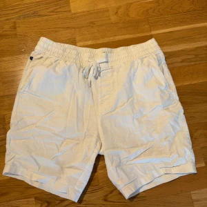 Vita linneshorts från Matinique - Snygga vita shorts från Matinique i luftig linnemix. De har elastisk midja med snörning och två sidofickor. Perfekta för varma dagar när du vill ha en clean och avslappnad look.