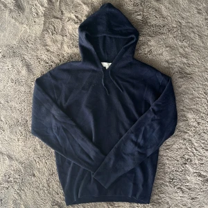 Mörkblå hoodie från Carmes i Kashmir  - Mysig mörkblå hoodie från Carmes i mjuk kashmir. Klassisk modell med huva och dragsko, samt långa ärmar och ribbade muddar. Skick 8/10. Hör gärna av er om ni har några funderingar!