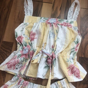 Blommig pyjamas med spets🌷🌸 - Superfin pyjamas i bomull med blommigt mönster i rosa och grönt på vit och gulrandig botten. De har loose fit, elastisk midja och volangdetaljer. Perfekta för sommarens varma dagar och ger en romantisk vintagekänsla. 🌸🌷❣️💕☀️