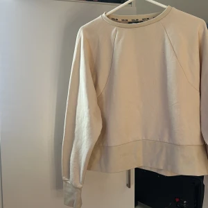 Beige sweatshirt från 157 - En stilren beige sweatshirt från 157 med rund halsringning och långa ärmar. Tröjan har en relaxed passform och är tillverkad i mjuk bomull, perfekt för en chill och enkel look. Passar grymt till jeans eller mjukisbyxor.