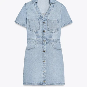 Jeansklänning - Snygg ljusblå jeansklänning med kort ärm, v-ringning och knappar hela vägen framtill. Klänningen har två bröstfickor, två sidofickor och två bakfickor.  Aldrig använd med lappen kvar på, säljer då den är för stor och kan inte returnera 