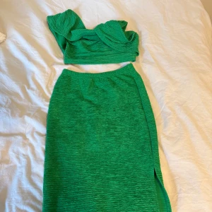 Grön långkjol med slits & topp - Snygg grön långkjol med slits på sidan. Kjolen har en cool, rynkad struktur i tyget som ger en unik look. Passar perfekt om du vill sticka ut med färg och stil. Elastisk midja för skön passform. Topp till