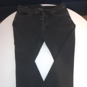 Helt nya Svarta loose fit jeans Jack & Jones - Säljer ett par svarta jeans från Jack & Jones, modell Loose/Eddie. Jeansen har en loose fit med raka ben och klassisk femficksdesign. Tillverkade i mjukt denimtyg som ger en avslappnad vibe. Perfekta för dig som gillar en bekväm och stilren look.