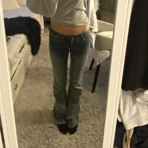 Lågmidjade Cheap Monday jeans  - Säljer ett par blå bootcut jeans från Cheap Monday med klassisk logga bak. Jeansen har låg midja, fem fickor och snyggt slitna detaljer framtill. Materialet är jeans i bomull och passformen är normal med utsvängda ben.