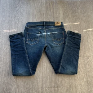 Blå jeans från Replay Wallyx - Snygga blå jeans från Replay, modell Wallyx. Klassisk femficksdesign med kontrastsömmar och Replay-logga på bakfickan. Jeansen har en rak passform och är tillverkade i slitstarkt bomullsjeansmaterial. Perfekta för en avslappnad och stilren look.