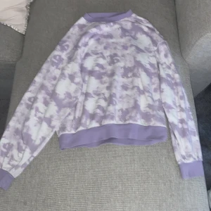 Lila och vit tie-dye sweatshirt - Superfin sweatshirt i lila och vitt tie-dye mönster. Tröjan har ribbade muddar vid ärmslut, hals och nederkant. Skön och avslappnad passform, perfekt till jeans eller mjukisbyxor. Tillverkad i mjukt bomullsmaterial och har långa ärmar.