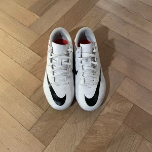 Vita Nike fotsallskor med svart swoosh - Skifteta footsall skor/ inne gympaskor💫Storlek 38 1/2 passar perfekt ✅Nypris ca 799, vårt pris 199✅ Andvänd ca en gång✅  funkar lika perfekt för gympan i skolan som den gör för fotsall 