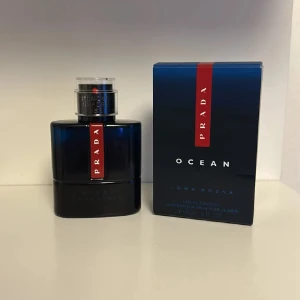 Prada Luna Rossa Ocean - Fräsch och modern parfym från Prada, Luna Rossa Ocean. Flaskan är djupblå med en elegant röd detalj och silvrig spraykork. Kommer i originalförpackning med matchande design. Perfekt för dig som gillar stilrena och exklusiva dofter.