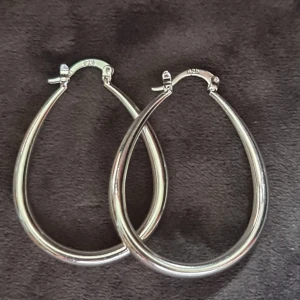 Droppformade örhängen i äkta silver - Snygga droppformade örhängen i äkta 925 silver. De är ca 4 cm långa och har en stilren, blank yta som ger en cool vibe. Perfekta för dig som gillar minimalistisk design och vill ha något som sticker ut lite extra.