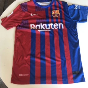 FC Barcelona matchtröja Nike - Säljer en FC Barcelona matchtröja , Nike med klassiska röda och blå vertikala ränder. Tröjan har korta ärmar, klubbmärke på bröstet och sponsortryck från Rakuten och UNICEF. Tillverkad i lätt och ventilerande material, perfekt för fotboll eller häng med polarna.