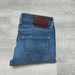 Replay Grover raka jeans blå  - Säljer ett par snygga Replay Grover jeans i klassisk blå tvätt. Modellen är straight fit med fem fickor, coola kontrastsömmar och läderpatch bak. Perfekta för dig som gillar raka jeans med en tidlös vibe.