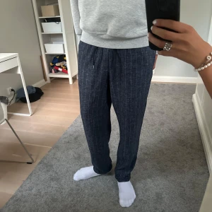 Randiga linnebyxor från Les Deux - Mörkblå linnebyxor från Les Deux med smala vita ränder. Byxorna har avslappnad passform, storlek XL men sitter som L. Jag är 187 cm och de sitter som på bilderna. Köptes i somras och knappast använda!