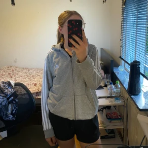 Adidas kofta  - Säljer en grå adidas kofta med vita sträck, storlek L, mycket bra skick! Säljer den för 100kr + frakt!