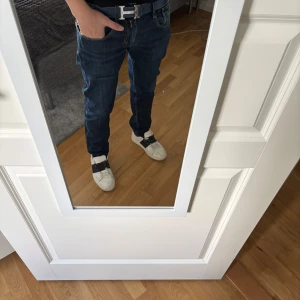 Replay Anbass jeans mörkblå herr - Säljer ett par snygga Replay Anbass jeans i mörkblå tvätt. Klassisk femficksmodell med raka ben och normal passform. Jeansen har diskreta slitningar och tydliga kontrastsömmar. Perfekta för dig som gillar stilrena och bekväma jeans.skriv om du har funderingar 