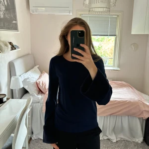 Mörkblå tröja med fuskpälsärmar - Säljer en mörkblå långärmad tröja med vida ärmar och snygga detaljer i fuskpäls längst ner på ärmarna. 