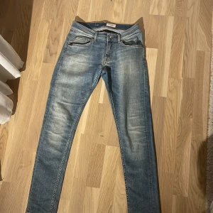 Blå skinny jeans Tiger of Sweden - Snygga blå skinny jeans från Tiger of Sweden med klassisk femficksdesign och ljusa slitningar framtill. Jeansen har normalhög midja, smal passform och är tillverkade i mjukt bomullstyg med stretch. Perfekta för en clean och stilren look.