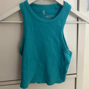 Turkos ribbad linnetopp från FSBN Sister - Turkos croppad linnetopp från FSBN Sister. Toppen är ribbad och ärmlös med rund halsringning. Perfekt för varma dagar och enkel att matcha med jeans eller shorts.