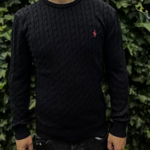 Svart kabelstickad tröja Polo Ralph Lauren - Svart kabelstickad tröja från Polo Ralph Lauren med rund halsringning och röd broderad logga på bröstet. Tröjan har lång ärm och ribbade muddar. Perfekt för dig som gillar klassisk och stilren look..      Nypris: 2395kr GORILLAPRIZE:1230kr             Skick:10/10 oöppnad          KVITTO MEDKOMMER 