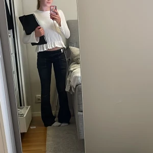 Vit långärmad blus med volang - Supersöt vit långärmad blus med volangkant nedtill. Tunn och lätt i materialet.