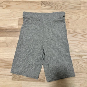 Grå shorts  - Gråa cykelshorts i mjukt och stretchigt bomullsmaterial. De har en enkel och clean design med midwaist passform och raka ben som slutar ovanför knäna. Perfekta för en chill och sportig look.