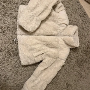 Beige teddyjacka med dragkedja - Supermjuk och fluffig teddyjacka i beige med hög krage och dragkedja framtill.  Storlek xxs, men oversize passar mig som har S 
