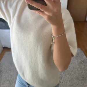 Vit stickad kortärmad tröja - Mysig vit stickad tröja med korta ärmar och rund hals. Tröjan har en enkel och clean look, perfekt att matcha med jeans eller kjol. Materialet känns mjukt och har en lätt fluffig yta. Passformen är normal och tröjan har ribbad kant vid halsen.