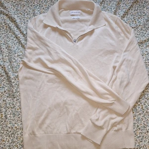 Beige half zip tröja These Glory Days - Snygg beige långärmad tröja från These Glory Days med krage och half zip-dragkedja framtill. Tillverkad i mjuk bomull som känns skön mot huden. Perfekt för dig som gillar stilrena och enkla plagg med en chill vibe. 