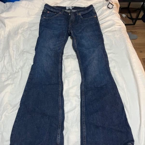 Blå bootcut jeans från 157, stl S - Snygga blå bootcut jeans från 157 i storlek S med kort benlängd. Klassisk femficksmodell med orangea sömmar och normalhög midja. Jeansen är tillverkade i ett robust denimtyg som ger en tidlös look och passar perfekt till sneakers eller boots.