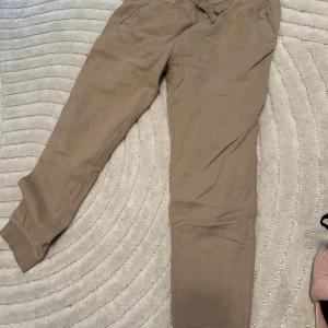 Beige mjukisbyxor med snörning - Säljer ett par beige mjukisbyxor med resår och snörning i midjan. Byxorna har fickor på sidorna och muddar vid bensluten. Perfekta för chill dagar eller när du vill vara extra bekväm. EXTREMT varma