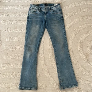 LTB Valerie bootcut jeans - Snygga bootcut jeans från LTB, modell Valerie, i ljusblå färg. Jeansen har låg midja, fem fickor och coola slitningar. Perfekt för dig som gillar en avslappnad men trendig look. Materialet är mjukt jeans med stretch för extra komfort.