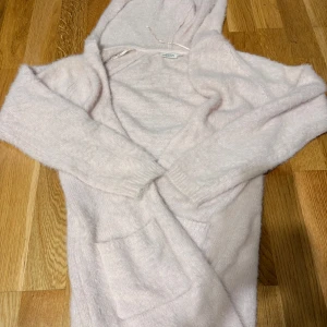 Ljusrosa hoodie från KappAhl - Supermjuk och fluffig ljusrosa hoodie från KappAhl med huva och stora fickor framtill. Perfekt för dig som gillar en chill och cozy stil. Långärmad och i stickat material som känns extra skönt under kyliga dagar.