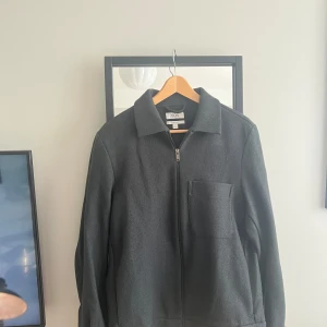 Mörkgrå overshirt/jacka  från COS - Stilren mörkgrå/grön jacka från COS med dragkedja framtill och en bröstficka. Använd 2-3 gånger. Superfint skick. Storlek S