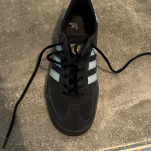 Adidas Spezial mörkblå sneakers mocka - Adidas Spezial sneakers i mörkblå mocka med ljusblå detaljer och klassiska vita ränder på sidorna. Skon har brun sula, snörning och rund tå. Perfekt för dig som gillar retrovibbar och streetstyle.