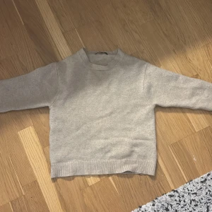 stickad tröja från Uniqlo - Mysig beige stickad tröja från Uniqlo i storlek S. Tröjan har rund halsringning, långa ärmar och ribbade muddar vid ärmslut och nederkant.