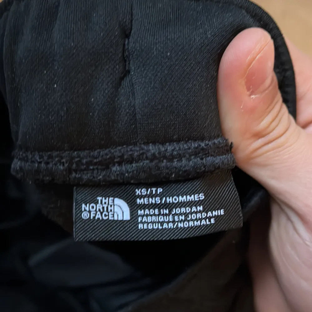 Svarta mjukisbyxor från The North Face med vit logga på låret. Byxorna har elastisk midja och är i en bekväm, avslappnad passform. Perfekta för chill eller träning.. Farkut & Housut.